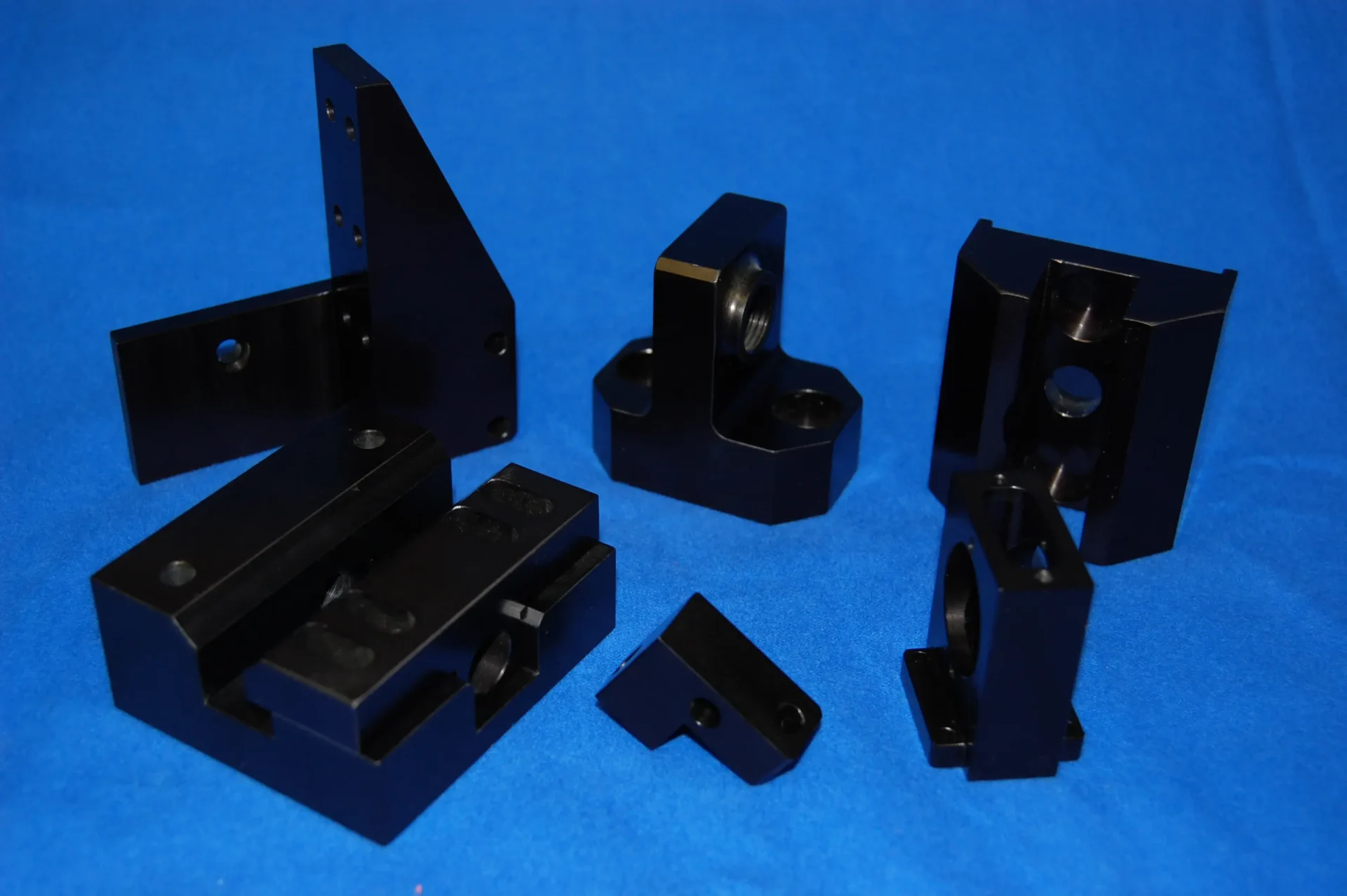 Various black plastic mechanical parts on a blue surface.