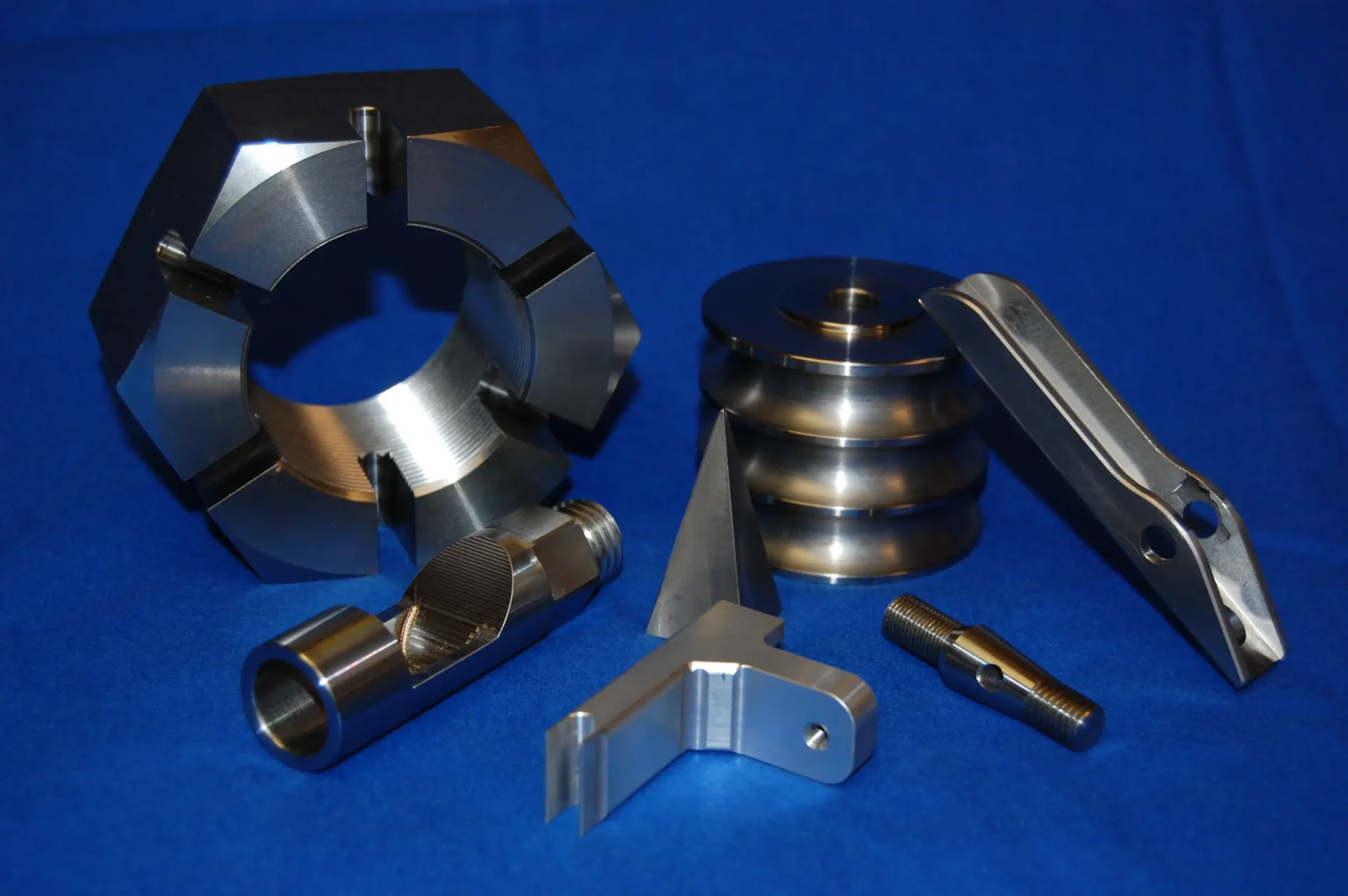 A set of shiny metal machine parts on a blue surface.